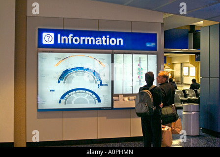 Passagiere, die Anzeigen von CRT-Monitoren am Flughafen für Abfahrts-und Ankunftszeiten Stockfoto