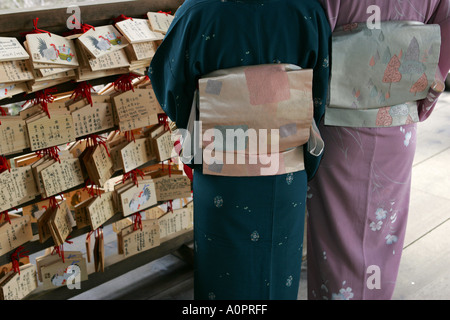 Zwei japanische Frauen tragen Traitional Kimono und hell farbige Seide Obi Gürtel lesen Gebet Tabletten in einem Tempel in Kyoto, Japan Stockfoto