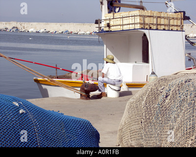 Angler Angeln mit Rute und Schnur neben einer kommerziellen Fischerboot, Puerto Deportivo de Fuengirola, Hafen von Fuengirola, Spanien Stockfoto