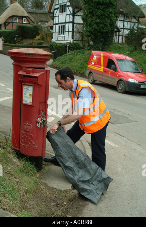 Postbote leert sich leerende Briefkasten Box in ländlicher Lage England UK Royal Mail Füllung sack Stockfoto