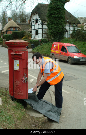 Säule Feld Postbote leert sich leerende Briefkasten in ländlicher Lage England UK Royal Mail löschen Feld Arbeit Beruf gesund Stockfoto