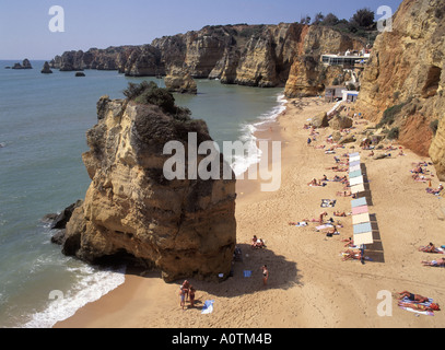 Algarve Praia Da Dona Ana sandigen Strand und Küste Sonne Schatten Parasoles auf Felsvorsprüngen mit Klippen entlang der Küste Stockfoto