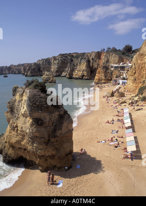 Algarve Praia Da Dona Ana sandigen Strand und Küste Sonne Schatten Parasoles auf Felsvorsprüngen mit Klippen entlang der Küste Stockfoto