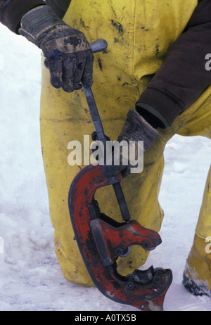 Öl Arbeiter tragen gelbe Overalls mit einem Rohrschneider im Schnee Stockfoto
