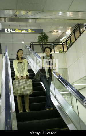 Niedrigen Winkel Blick auf zwei junge Frauen stehen auf einer Rolltreppe und lächelnd Stockfoto