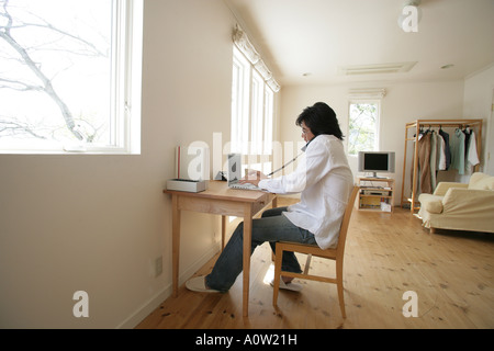 Seitenansicht eines jungen Mann mit einem Laptop und am Telefon sprechen Stockfoto