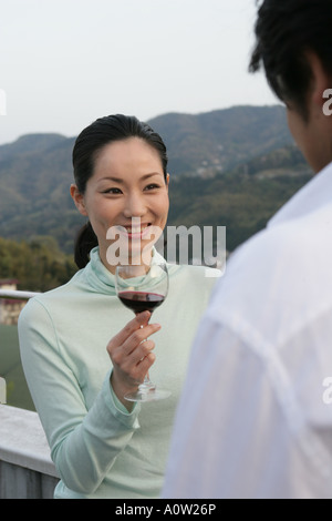 Junge Frau hält ein Weinglas und Blick auf einen jungen Mann Stockfoto