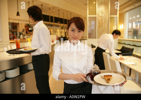 Porträt von einer Kellnerin stand in der Küche mit zwei Kellner im Hintergrund Stockfoto