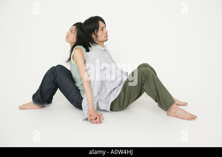 Seitenansicht eines jungen Paares sitzen Rücken an Rücken Stockfoto