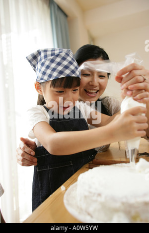 Mitte Erwachsene Frau und ihrer Tochter einen Kuchen dekorieren Stockfoto