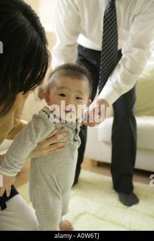 Portrait eines Babyjungen stehend mit Hilfe seiner Eltern Stockfoto