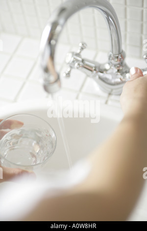 Erhöhte Ansicht einer Frau s Hand füllen Wasser in ein Glas aus einem Wasserhahn Stockfoto