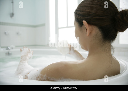 Rückansicht einer jungen Frau in einem Schaumbad Stockfoto