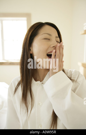 Nahaufnahme einer jungen Frau, die ihren Mund mit der Hand abdecken und Gähnen Stockfoto