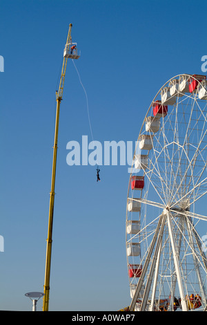 Mann auf einen Bungee-Sprung in der Nähe ein großes Rad in einem Vergnügungspark Stockfoto