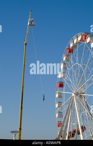 Mann auf einen Bungee-Sprung in der Nähe ein großes Rad in einem Vergnügungspark Stockfoto