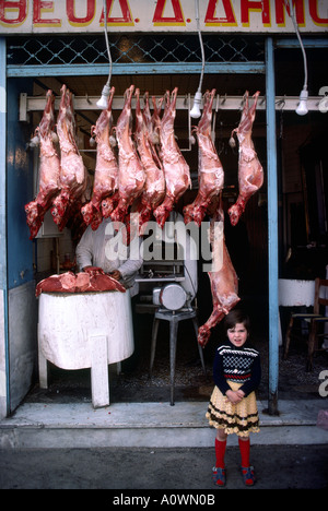 Ein junges Mädchen steht vor einer Metzgerei mit ganzen Schafe in Athen Griechenland Stockfoto