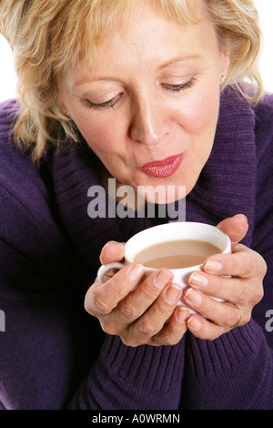 Reife Frau halten und trinken eine Tasse heißen Tee süßen Erwärmung Stockfoto