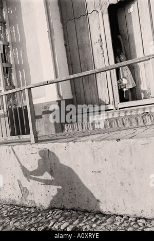 Kuba-TRINIDAD-Jugendliche spielen Baseball werfen ihre Schatten an der Wand, wie ein Kind nach Hause kommt Stockfoto