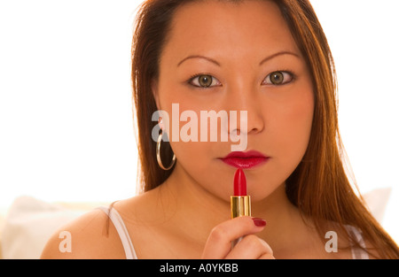 Nahaufnahme einer jungen asiatischen Frau, die roten Lippenstift aufträgt. USA Stockfoto
