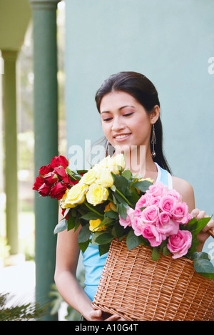 Nahaufnahme einer jungen Frau hält einen geflochtenen Korb mit Blumen Stockfoto