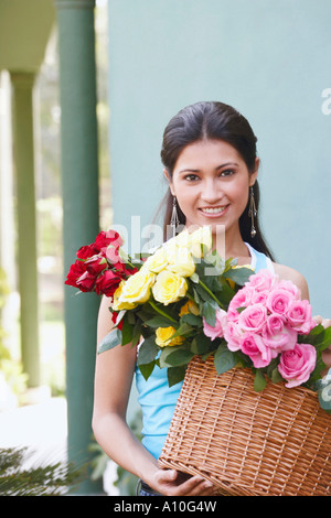 Porträt einer jungen Frau mit einem Korb voller Blumen Stockfoto