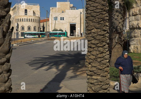 Israel Jerusalem Stadtmauern promenade in der Nähe von Rathaus Blick auf Rathaus mit palästinensischen Frau zu Fuß und palm-Baum-Stämme in fr Stockfoto