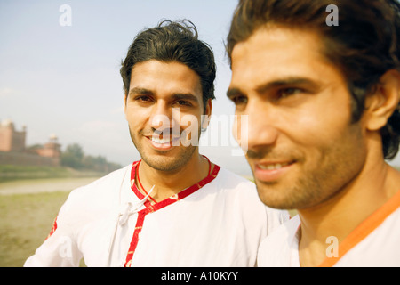 Nahaufnahme von zwei jungen Männern, die lächelnd zusammen am Ufer des Flusses, Agra, Uttar Pradesh, Indien Stockfoto