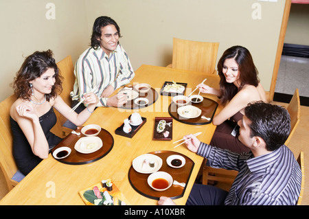 Vogelperspektive Blick auf zwei junge Paare am Esstisch sitzen und Lächeln Stockfoto