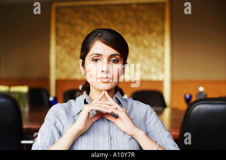 Porträt einer Geschäftsfrau, die mit ihren Händen unter dem Kinn sitzen Stockfoto