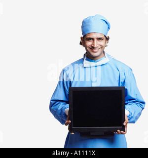Porträt eines männlichen Arztes trägt chirurgische Peelings und hält einen laptop Stockfoto