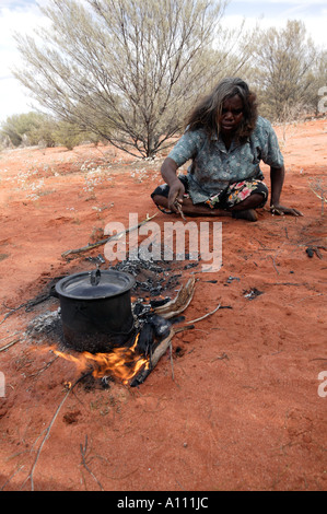 Aborigine-Frau zieht eine Witchetty Grub von der Wurzel des Witchetty Busch, Anangu Pitjantjara Heimat, South Australia Stockfoto