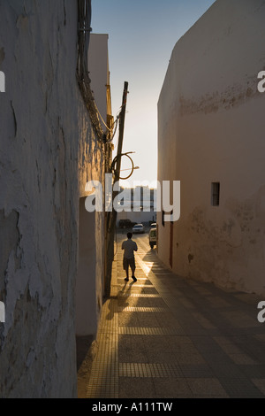 Ein Mann geht eine schmale Gasse in eine traditionelle spanische Stadt in der frühen Abendsonne Ayamonte Huelva Spanien EU Stockfoto