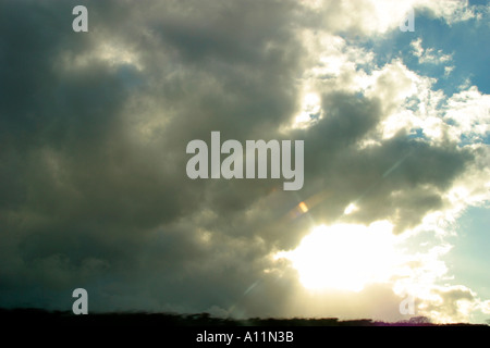 Sonne verdeckt hinter flauschigen Wolken am blauen Himmel Stockfoto