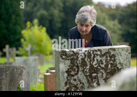 Frau betrachten Namen auf Grabstein Stockfoto