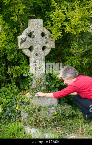 Frau betrachten Namen auf Grabstein Stockfoto