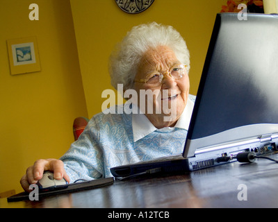 Ältere Dame Laptop-Computer fasziniert selbstbewusst lächelnd erstaunt über zu Hause lernen Bildung mit ihrem neuen Laptop-Computer und seine neue Technologie Stockfoto