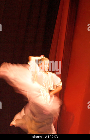 Junge Tänzerin in Quirlen langen Rock vor roten Vorhang weiß Stockfoto
