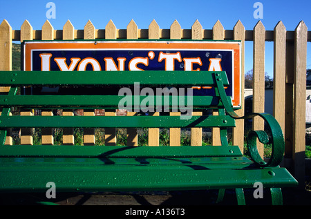 Grüne Sitzbank und ein altes umgearbeitet Lyons Tee Werbeschild am Corfe Bahnhof in Dorset county England UK Stockfoto
