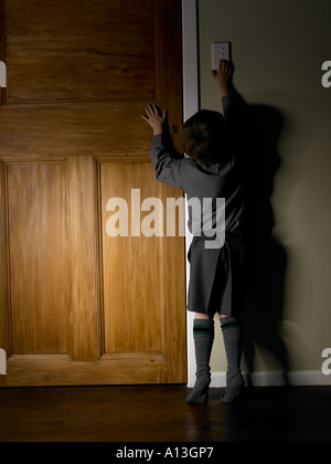 Schulkind in Uniform der Shorts und t-Shirt, die kämpfen, um das Licht einzuschalten Stockfoto