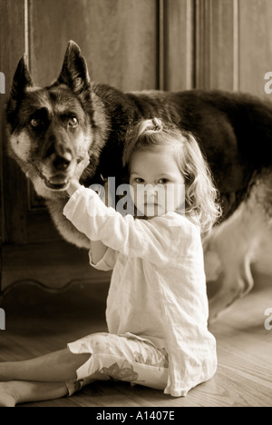 zwei Jahre altes Mädchen sitzen auf dem Boden halten ihren Hund am Kragen Stockfoto