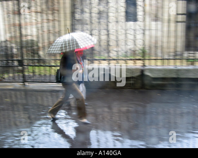 verschwommenes Bild der Fußgänger mit Schirm im Regen Stockfoto