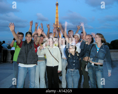 Momentaufnahme der Teenager Schule Gruppe winken in die Kamera vor Eiffelturm in der Abenddämmerung Paris Frankreich Stockfoto