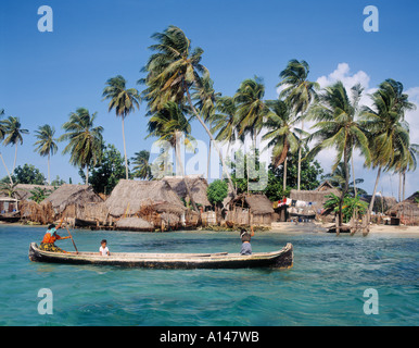 San Blas Inseln, Republik von Panama.  Cuna indische Kanu paddelten von Frau mit zwei Kindern.  Dorf hinter. Stockfoto