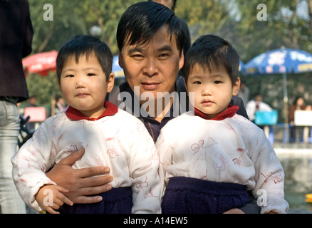 Zwei chinesische twin Kind Schwestern mit identische Kleidung, posiert mit ihrem Onkel in Shanghai, China. Stockfoto