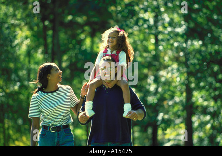 Eine afroamerikanische Familie im Park spazieren reitet die Tochter auf ihren Papa Schultern Stockfoto