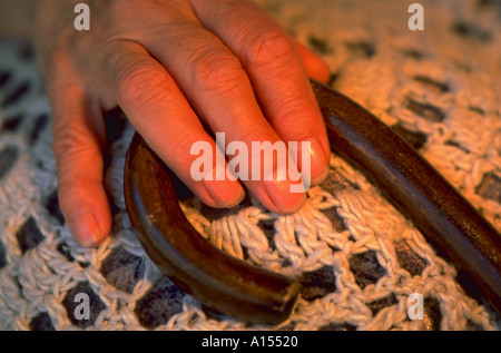 Eine ältere Hand hält sich an den Griff mit einem Rohrstock Stockfoto