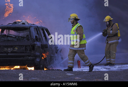 Feuerwehrleute in der Szene von einem brennenden Auto. Stockfoto