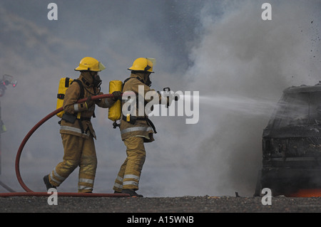 Zwei Feuerwehrleute, die Bekämpfung von einem brennenden Auto. Stockfoto