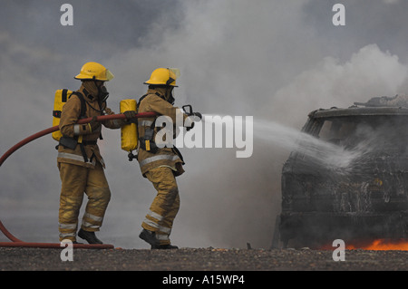 Zwei Feuerwehrleute, die Bekämpfung von einem brennenden Auto. Stockfoto